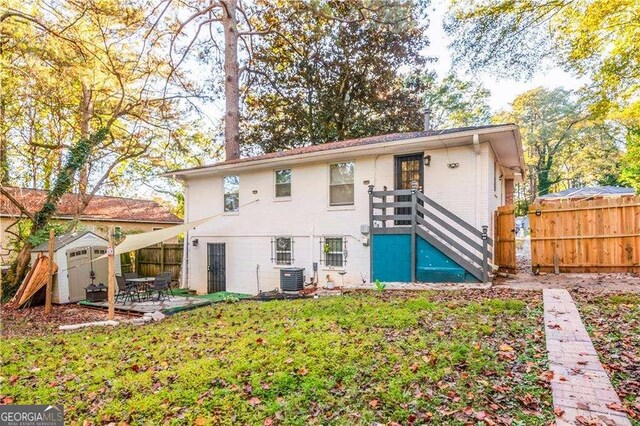 back of property with a shed, a yard, and central AC