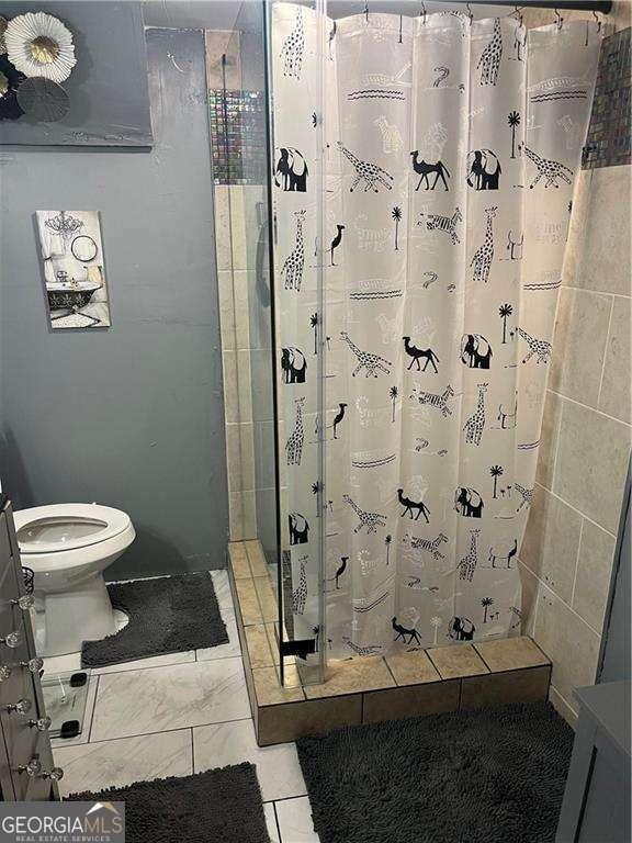 bathroom with toilet, a shower with curtain, and tile patterned floors