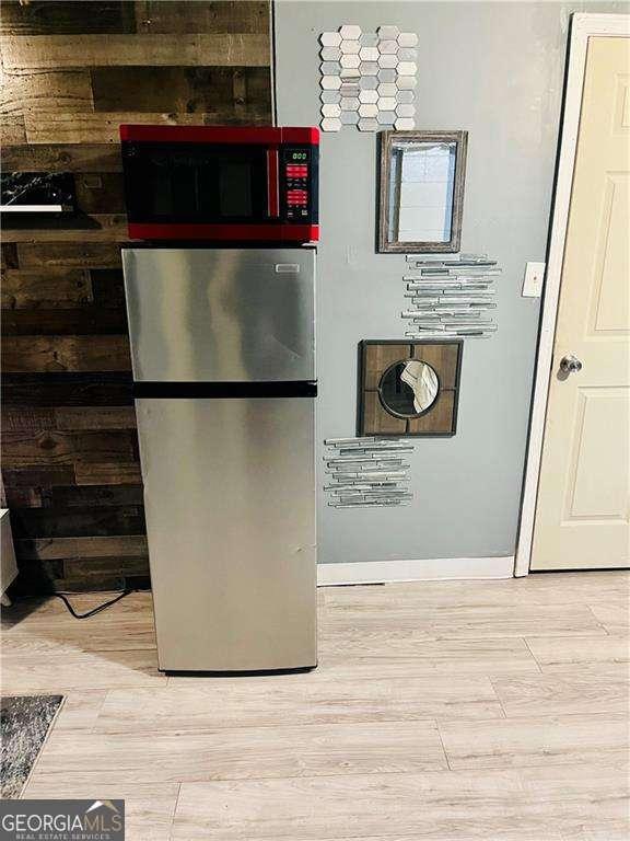 room details with stainless steel refrigerator and hardwood / wood-style flooring