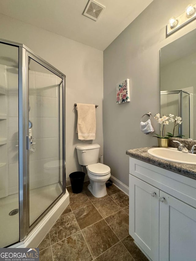 bathroom featuring vanity, toilet, and a shower with door