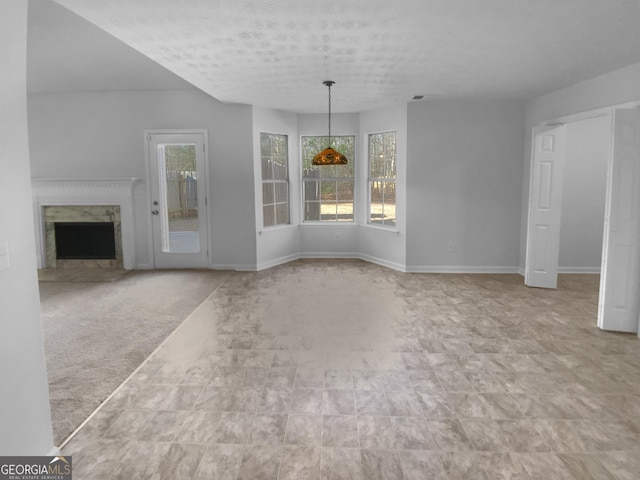 unfurnished living room with a high end fireplace, light colored carpet, and a wealth of natural light