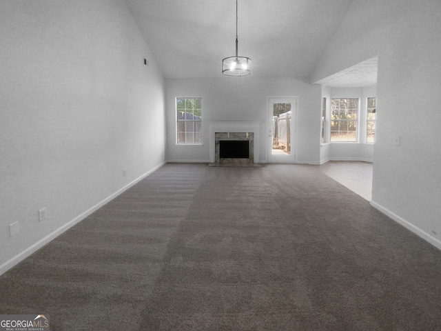 unfurnished living room featuring dark colored carpet, a healthy amount of sunlight, lofted ceiling, and a fireplace