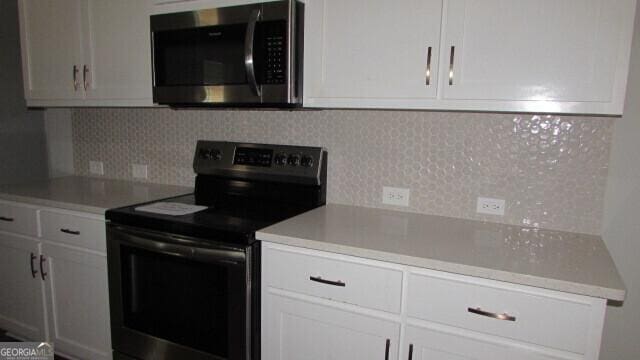 kitchen featuring decorative backsplash, white cabinets, and stainless steel appliances