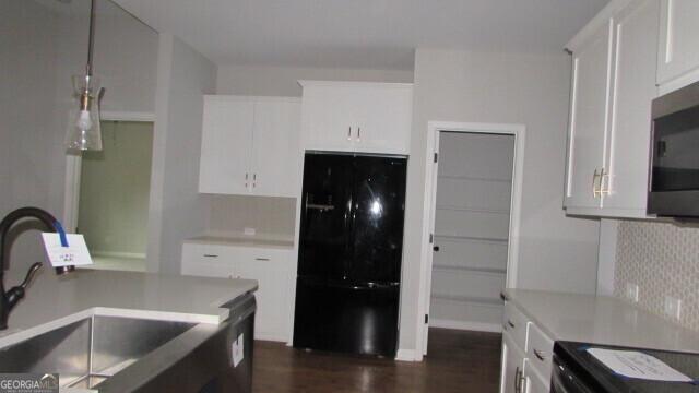 kitchen with black appliances, dark hardwood / wood-style floors, white cabinetry, and sink