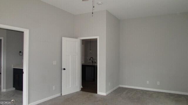 unfurnished bedroom featuring sink, carpet floors, and a high ceiling