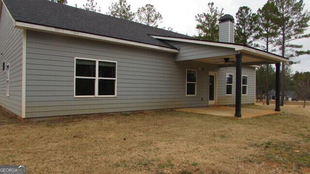 back of property with a yard and a patio