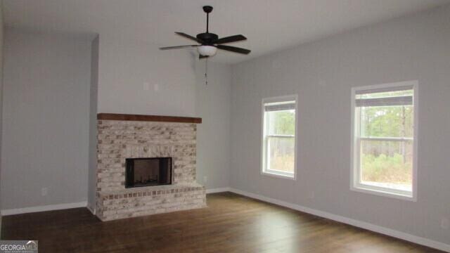 unfurnished living room with ceiling fan, a fireplace, and dark wood-type flooring