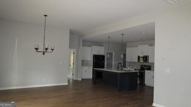 kitchen with white cabinetry, stainless steel appliances, a notable chandelier, pendant lighting, and a kitchen island with sink