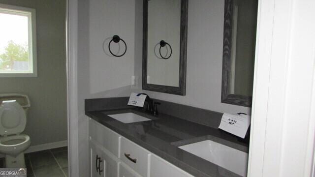 bathroom with toilet, vanity, and tile patterned floors