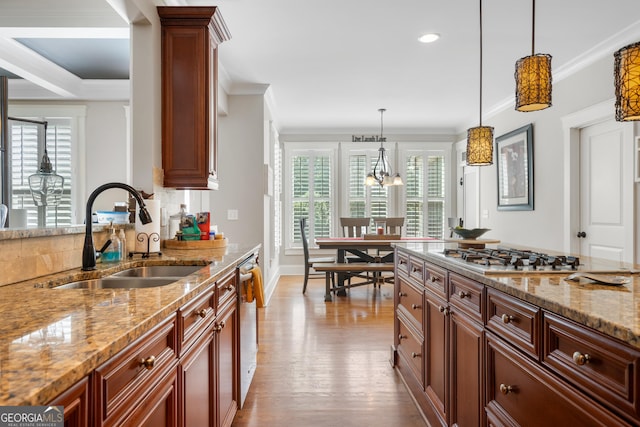 kitchen featuring sink, hanging light fixtures, ornamental molding, light stone countertops, and stainless steel appliances