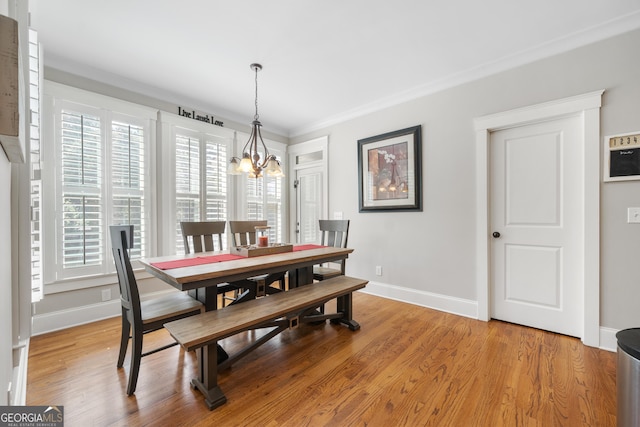 dining space with ornamental molding, light hardwood / wood-style flooring, and a chandelier