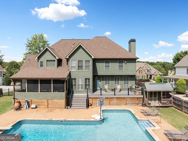 back of property with a fenced in pool and a patio