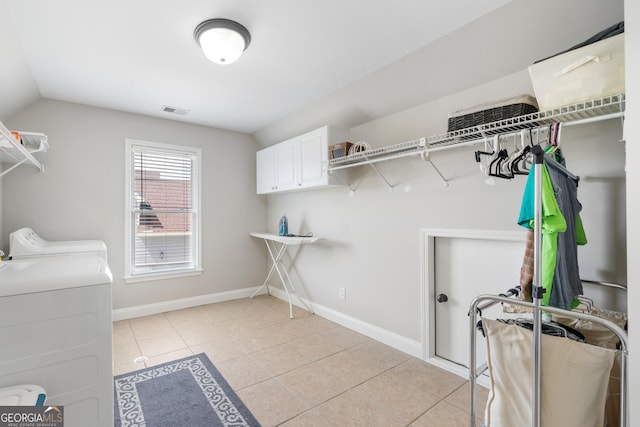 laundry room with washer and dryer, cabinets, and light tile patterned flooring