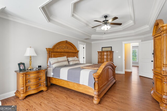 bedroom featuring a tray ceiling, ceiling fan, hardwood / wood-style floors, and ornamental molding