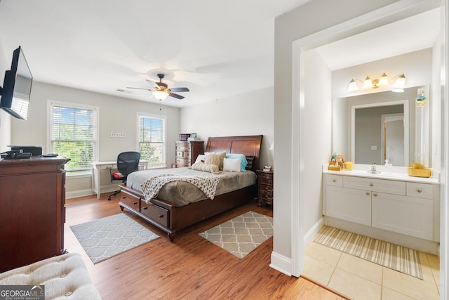 bedroom featuring ceiling fan, light wood-type flooring, sink, and connected bathroom