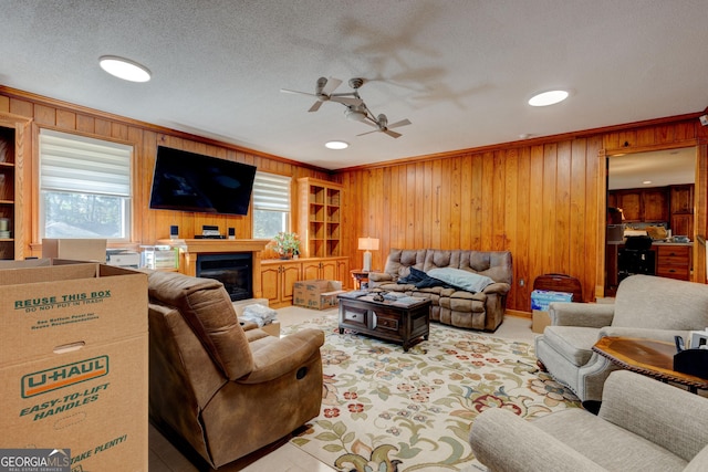 living room with ceiling fan, crown molding, a healthy amount of sunlight, and wooden walls