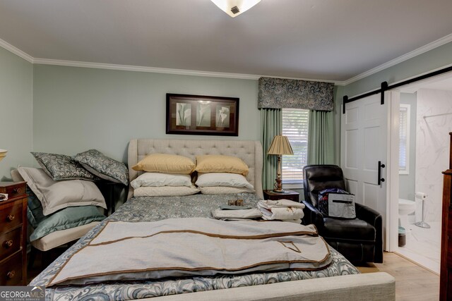 bedroom with light wood-type flooring, a barn door, ensuite bath, and crown molding