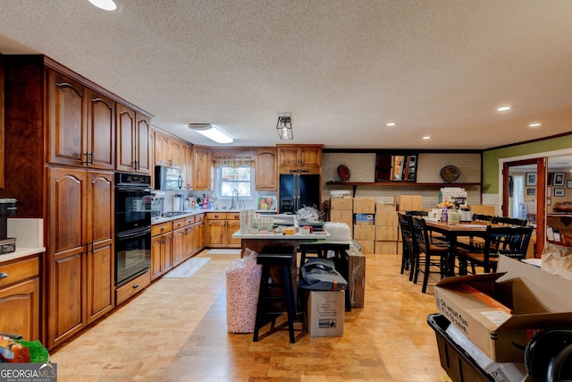 kitchen featuring sink, a center island, a kitchen bar, black appliances, and ornamental molding