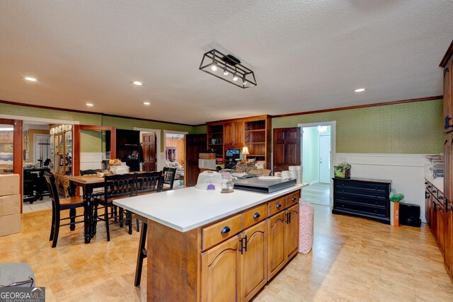 kitchen with a textured ceiling, a kitchen island, crown molding, and a breakfast bar area