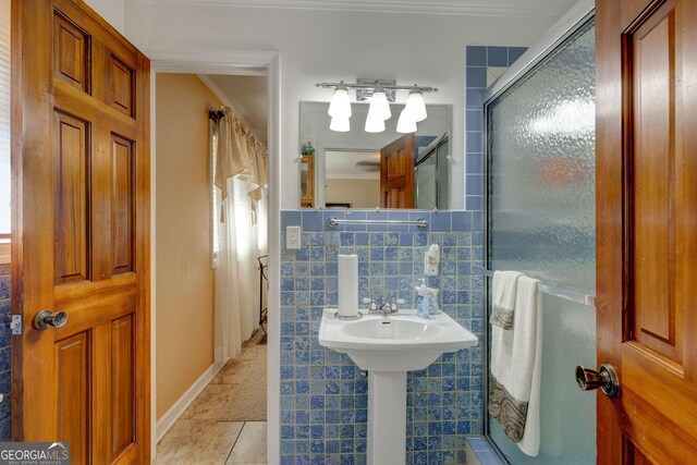 bathroom with tile patterned flooring, decorative backsplash, ornamental molding, tile walls, and a shower with shower door