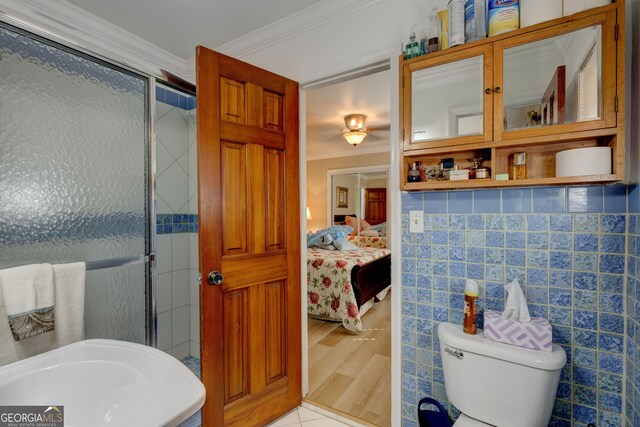 bathroom featuring tile patterned floors, an enclosed shower, crown molding, and tile walls