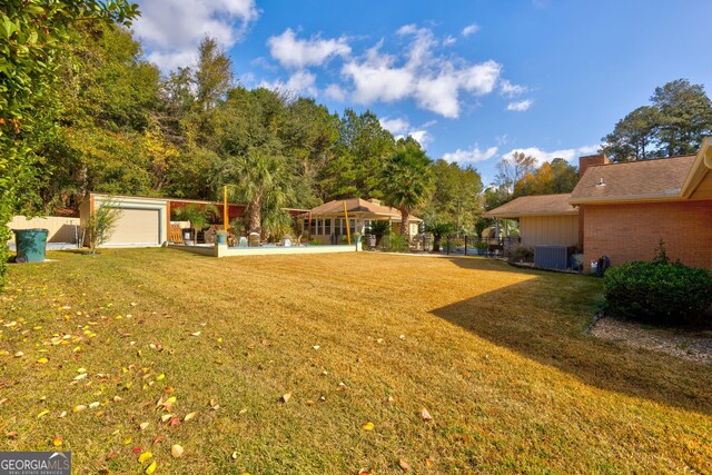 view of yard with an outdoor structure, central AC unit, and a garage