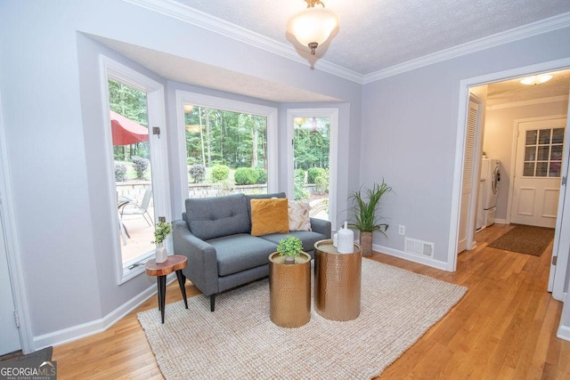 sitting room with light wood-type flooring, a wealth of natural light, and crown molding