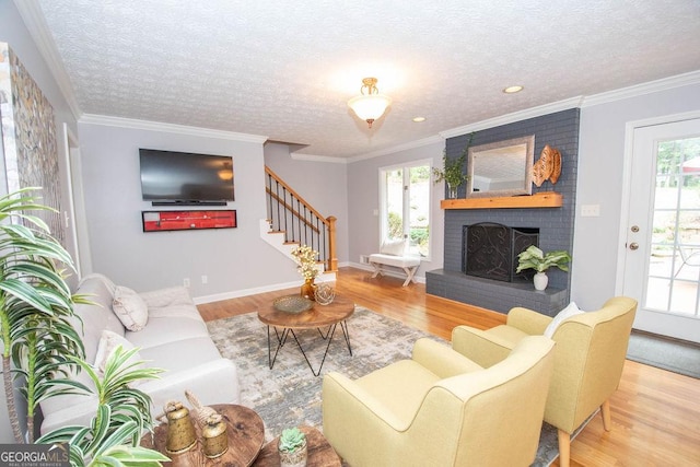 living room with a textured ceiling, hardwood / wood-style floors, crown molding, and a fireplace