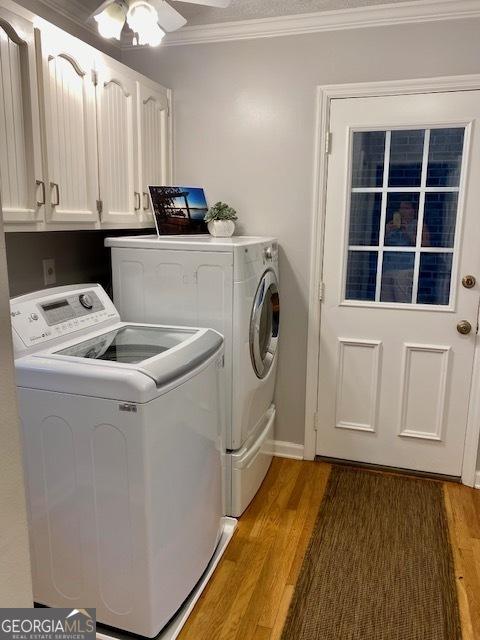 laundry room featuring washer and clothes dryer, dark wood-type flooring, cabinets, ornamental molding, and ceiling fan