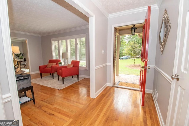 foyer entrance with a textured ceiling, ornamental molding, and hardwood / wood-style floors