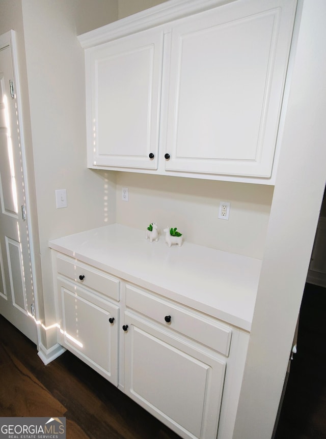 bar with dark hardwood / wood-style flooring and white cabinetry