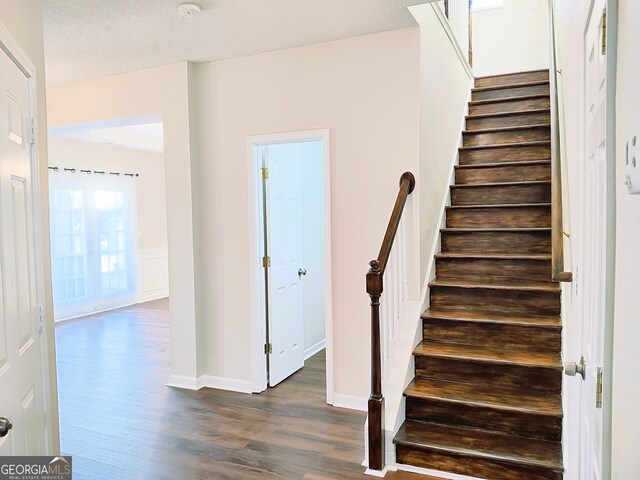 staircase with wood-type flooring and a textured ceiling