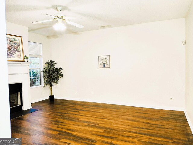 unfurnished living room featuring ceiling fan and dark hardwood / wood-style flooring