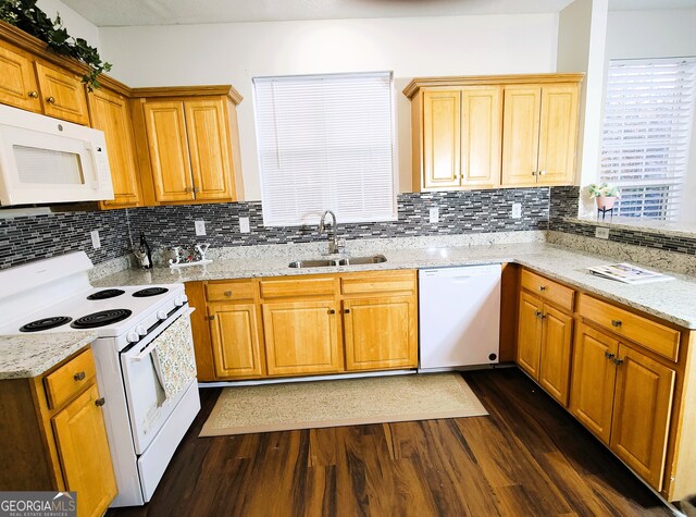 kitchen featuring tasteful backsplash, light stone counters, white appliances, dark wood-type flooring, and sink