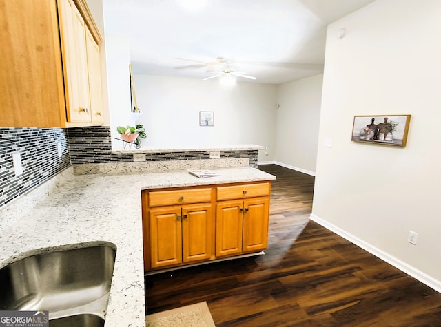 kitchen with decorative backsplash, ceiling fan, dark hardwood / wood-style flooring, and light stone countertops