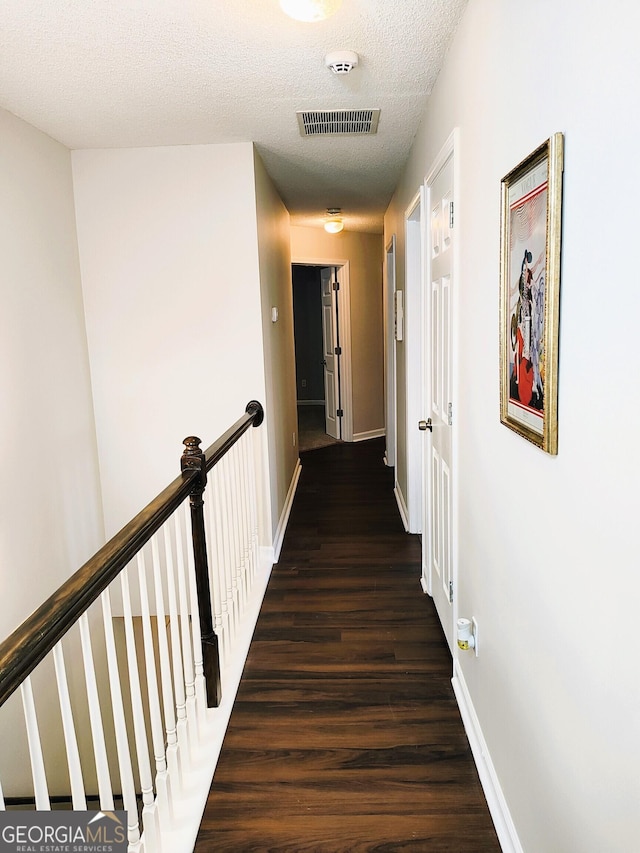 hallway featuring a textured ceiling and dark wood-type flooring