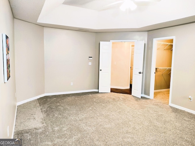 unfurnished bedroom with carpet flooring, ceiling fan, a walk in closet, and a closet