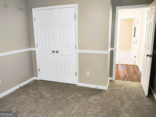 unfurnished bedroom with a closet and dark colored carpet