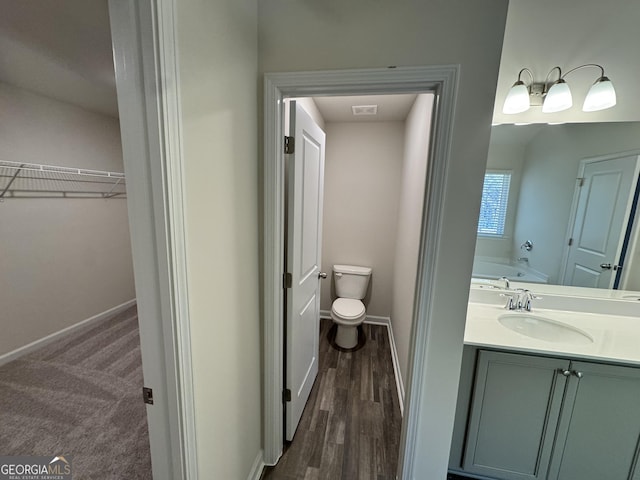 bathroom with vanity, hardwood / wood-style flooring, toilet, and a bathtub