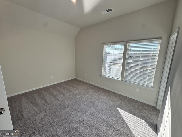 unfurnished room featuring carpet and vaulted ceiling