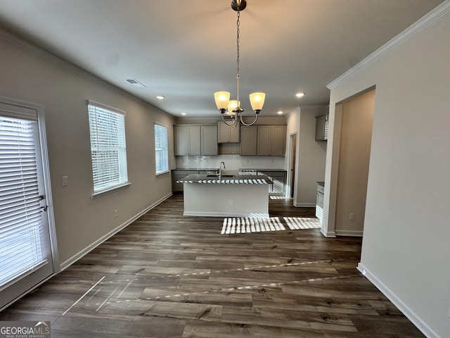 kitchen with gray cabinetry, sink, an island with sink, pendant lighting, and ornamental molding