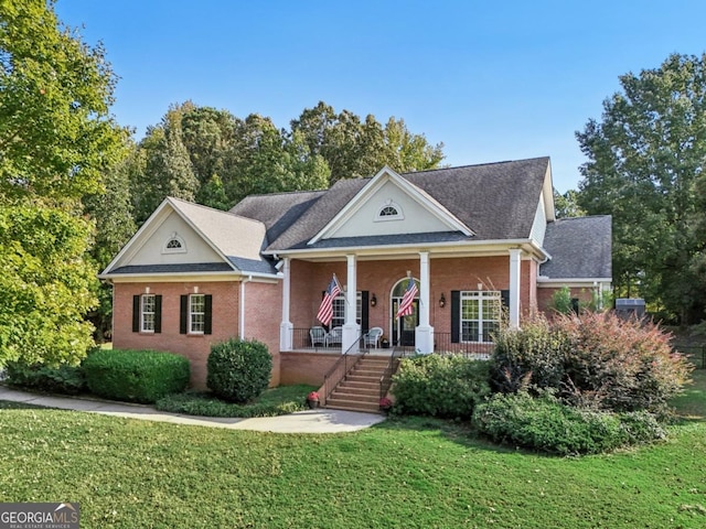 neoclassical / greek revival house with a porch, a front lawn, and brick siding