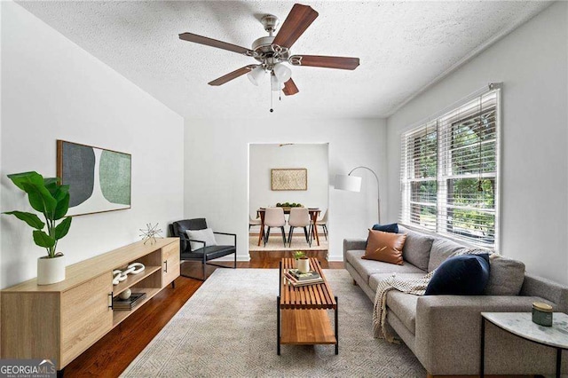 living room featuring ceiling fan, dark hardwood / wood-style floors, and a textured ceiling