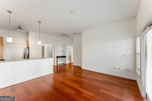 unfurnished living room with hardwood / wood-style floors and rail lighting