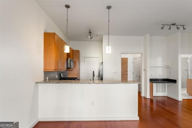 kitchen featuring kitchen peninsula, stove, light stone countertops, dark hardwood / wood-style floors, and hanging light fixtures