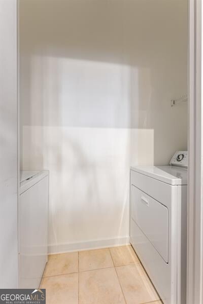 clothes washing area with washer and dryer and light tile patterned floors