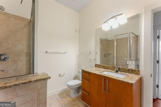 bathroom with tiled shower, tile patterned flooring, vanity, and toilet