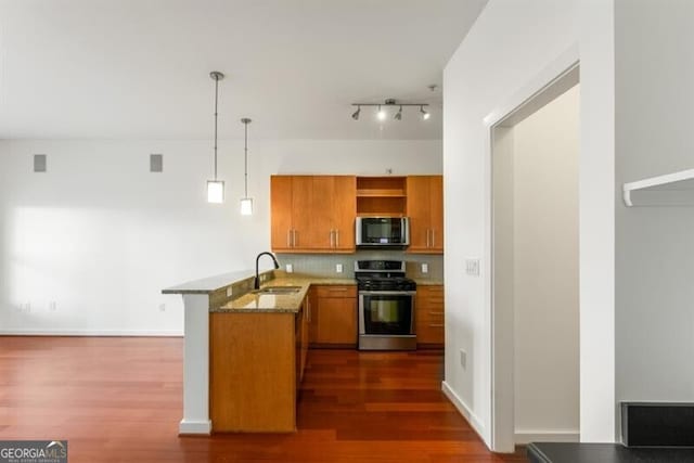 kitchen featuring kitchen peninsula, gas range, sink, dark hardwood / wood-style floors, and hanging light fixtures