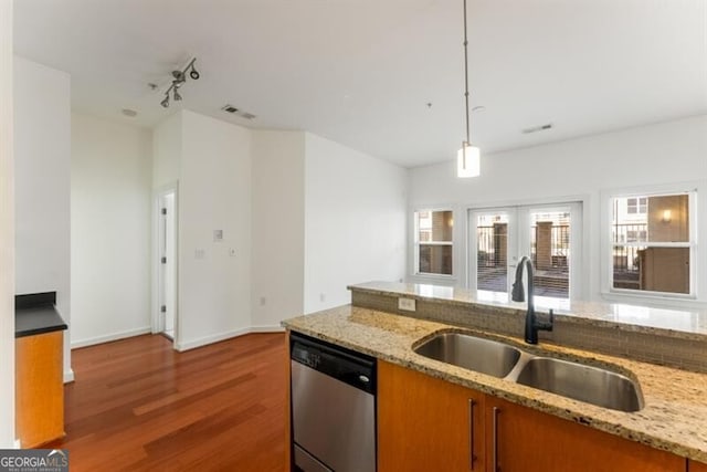 kitchen with dishwasher, pendant lighting, light stone counters, and sink