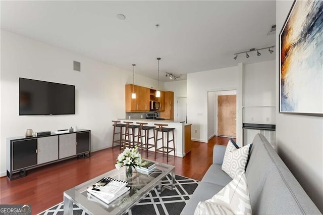 living room with dark wood-type flooring and track lighting